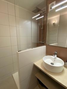 a white bathroom with a sink and a mirror at L'Arbousier in Rayol-Canadel-sur-Mer