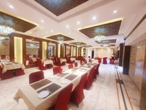 a restaurant with white tables and red chairs at Hotel Shrinath Palace in Jhānsi