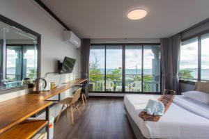 um quarto de hotel com uma cama, uma secretária e janelas em Pimpimarn Hotel em Mae Pim