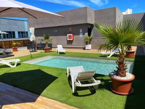 a swimming pool with a chair and a palm tree at Hotel BESTPRICE Alcalá in Madrid