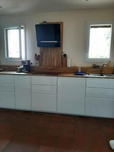 a kitchen with white cabinets and a tv on the wall at Au cabanon de Lisle in Lisle-sur-Tarn