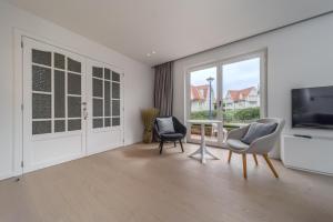 een woonkamer met 2 stoelen en een flatscreen-tv bij Le Calme des Dunes in Koksijde