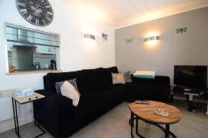 un sofá negro en una sala de estar con un reloj en la pared en PORT 40 2 - apartamento céntrico, en L'Estartit