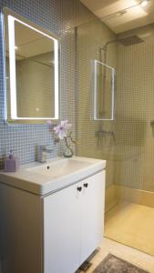 a bathroom with a sink and a mirror and a shower at Beachfront 2BR Apartment with Balcony and Sea View, Biser Mora in Rafailovici