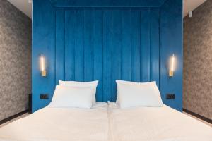 a bedroom with a blue wall and a bed with two pillows at Lotus Luxury Rooms in Varna City