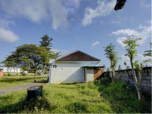 ein kleines Gebäude auf einem Feld neben einem Zaun in der Unterkunft SPOT ON 92855 Griya Sandi Syariah Rogojampi in Banyuwangi