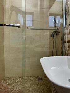baño con puerta de ducha de cristal y lavamanos en Westlands Tower - Ghana Villas, en Accra