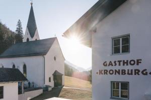 ツァムスにあるGasthof Kronburgの大聖の地形を読む看板を持つ教会