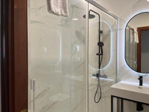 a shower with a glass door next to a sink at H Pelayo Auto Check-In Rooms in Noja