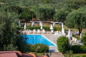 una piscina con sombrillas y sillas blancas en Relais d 'Itria, en Grottaglie