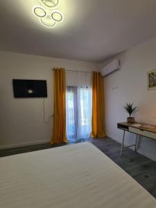 a bedroom with a large white bed and a television at The Green House in Timişoara