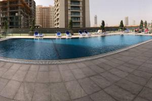 a large swimming pool with chairs and lawn chairs at Sweet studio in Dubai Sports City in Dubai