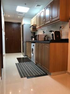 a kitchen with wooden cabinets and a washer and dryer at Sweet studio in Dubai Sports City in Dubai