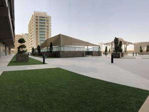 un gran edificio con césped delante en Sweet studio in Dubai Sports City, en Dubái
