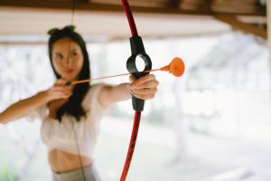 a woman holding onto a bow and arrow at Bor Saen Pool Villa in Bor Saen