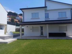 a white house with a lawn in front of it at Vista a las Cíes in Moaña