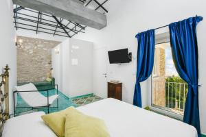 sypialnia z niebieskimi zasłonami, łóżkiem i oknem w obiekcie Albeca Boutique Hotel - Relais de charme sul mare w mieście Castellabate