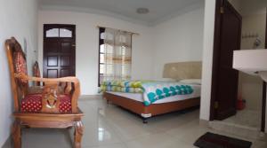 ein Schlafzimmer mit einem Bett und einem Stuhl darin in der Unterkunft WISMA SIBAYAK Guesthouse BERASTAGI in Berastagi