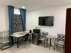 Zimmer mit einem Tisch, Stühlen und einem TV in der Unterkunft Luxury House with 3 bedrooms & balcony-terrace in Ho-Chi-Minh-Stadt
