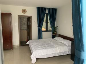 a bedroom with a bed and a window with blue curtains at Luxury House with 3 bedrooms & balcony-terrace in Ho Chi Minh City