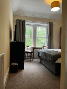 1 dormitorio con cama, mesa y ventana en Norwood Guesthouse-Loch Lomond, en Balloch