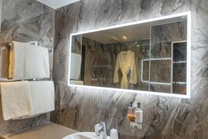 a bathroom with a sink and a mirror and a robe at Marks Tey Hotel Colchester in Colchester