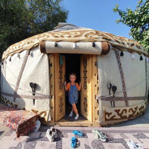 a child standing in the doorway of a play tent at Agat Yurt Camp in Kaji-Say