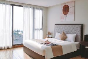 um quarto com uma cama grande e janelas grandes em KIKOZO DA NANG Hotel em Da Nang