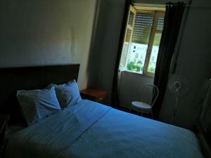 1 dormitorio con 1 cama con edredón azul y ventana en Sasimi Nice Hostel, en Braga
