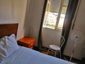 a bedroom with a bed and a window with a fan at Sasimi Nice Hostel in Braga