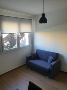 Sofá azul en la sala de estar con ventana en La Casa de Papel - Berlino - Self Check in, Smart Tv, tutti i confort, nuova costruzione, en Cavarzere