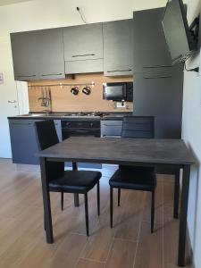 uma cozinha com uma mesa de madeira e 2 cadeiras em La Casa de Papel - Berlino - Self Check in, Smart Tv, tutti i confort, nuova costruzione em Cavarzere
