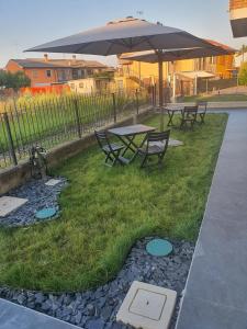 two picnic tables and an umbrella on the grass at La Casa de Papel - Self Check in, Smart Tv, tutti i confort, appartamento privato non condiviso in Cavarzere