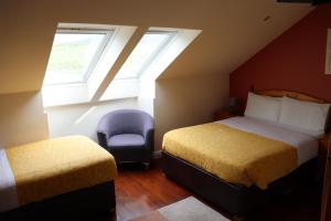 The Old Pier Guest Accommodation, bed only, no breakfast في Ballydavid: غرفة نوم بسريرين وكرسي ونافذة