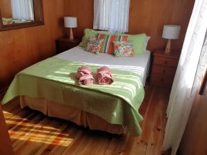 a bedroom with a bed with two pink slippers on it at Nabuco Estate Bure Rentals in Naweni