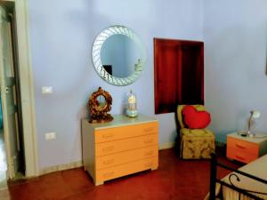 una camera da letto con cassettiera, specchio e sedia di Casa vacanza zia Ersilia a Rotondi
