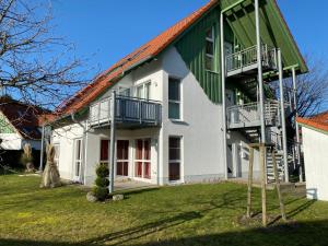 a large white house with a green roof at Dünenresidenz Karlshagen - Ferienwohnung am Gingsterweg in Ostseebad Karlshagen