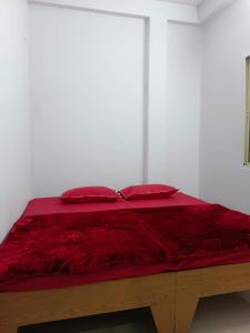1 cama con manta roja y 2 almohadas en Shree Maruti Guest House, en Ujjain