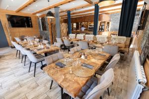 un ristorante con tavoli in legno e sedie bianche di Hotel Edelweiss ad Auron