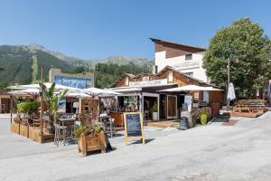 einen Markt mit Tischen, Stühlen und Sonnenschirmen auf einer Straße in der Unterkunft Hotel Edelweiss in Auron