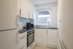 a kitchen with white cabinets and a sink and a window at Newly renovated 1-Bed Apartment in Aalborg in Aalborg