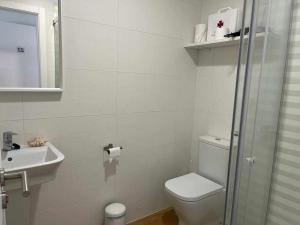 a white bathroom with a toilet and a sink at Mar de Queiruga 21 Enxa in Porto do Son