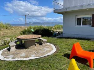 una mesa de picnic y dos sillas de plástico frente a una casa en Mar de Queiruga 22 Tarrío, en Porto do Son