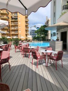una terrazza con tavoli, sedie e piscina di Charlie in Pesaro a Pesaro