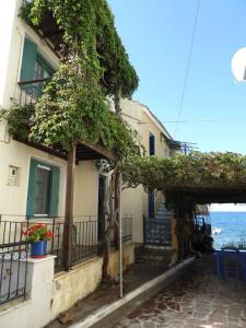 a building with ivy growing on it next to the ocean at Pinelopi Holiday House in Melínta