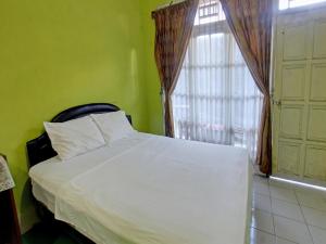 a bedroom with a white bed and a window at OYO 92849 Hotel Dienda Hayu in Lombok