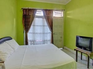 una camera con letto, TV e finestra di OYO 92849 Hotel Dienda Hayu a Lombok