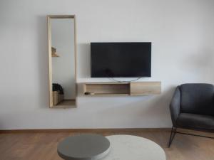a living room with a tv and a chair and a mirror at Flamingo in Hanioti