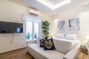 ein weißes Wohnzimmer mit einem Sofa und einem TV in der Unterkunft Greek Island in Athen