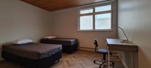 Zimmer mit 2 Betten, einem Schreibtisch und einem Fenster in der Unterkunft Kattohuoneisto keskustassa in Lieksa